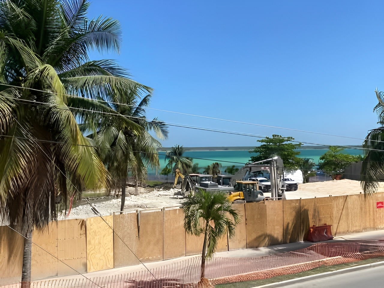 "Construcción suspendida de un hotel en Bacalar, con la Laguna de Bacalar de fondo y maquinaria en el sitio de obra."
