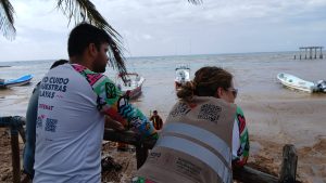 Marinos y voluntarios trabajando juntos en la playa El Recodo para limpiar el sargazo acumulado.