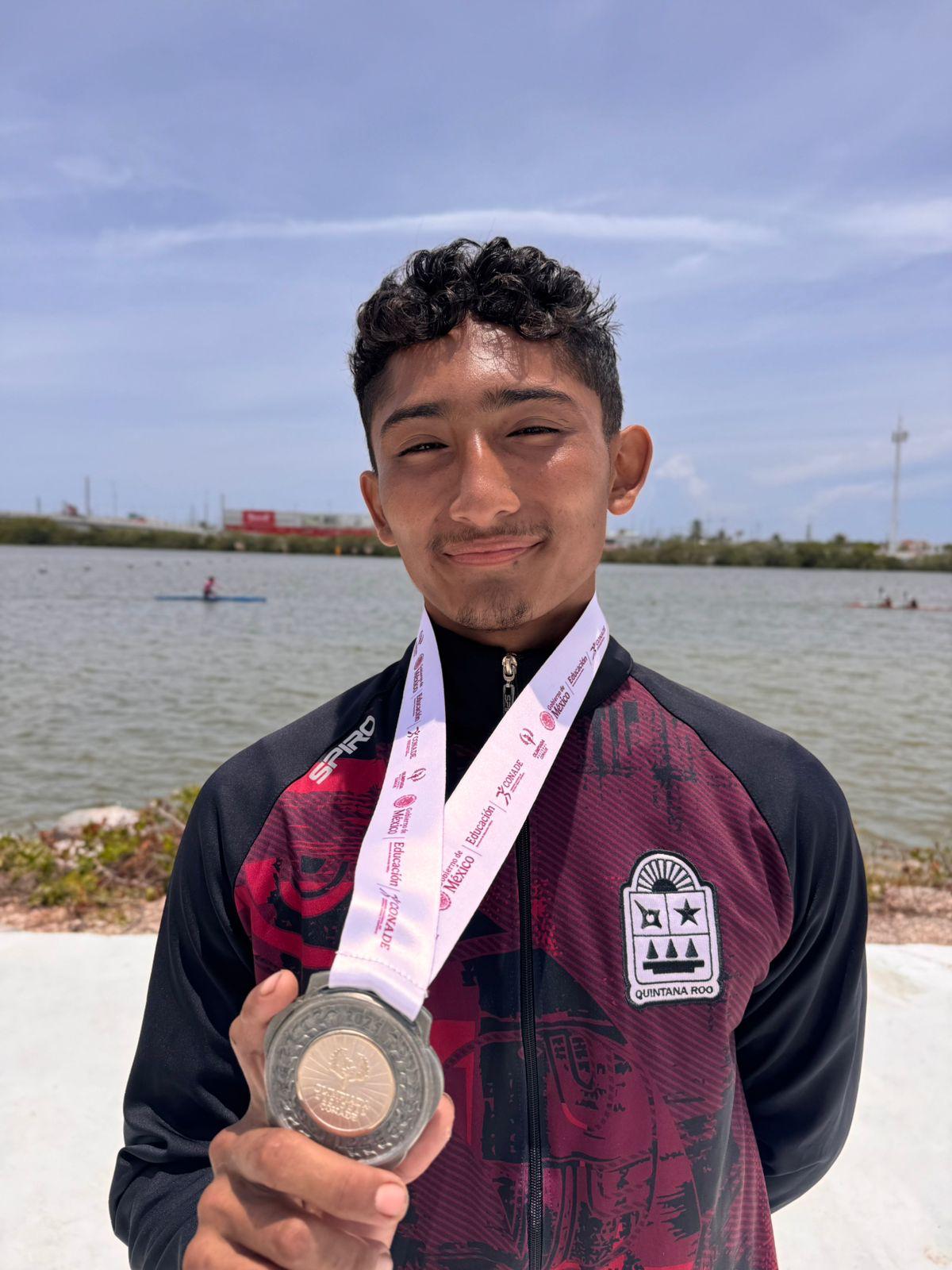 Héctor Gabriel Gutiérrez Paz en el podio, mostrando su medalla de plata en canotaje quintanarroense.