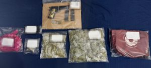 Un agente de la SSC examina los indicios asegurados, incluyendo el arma de fuego y las bolsas de marihuana.