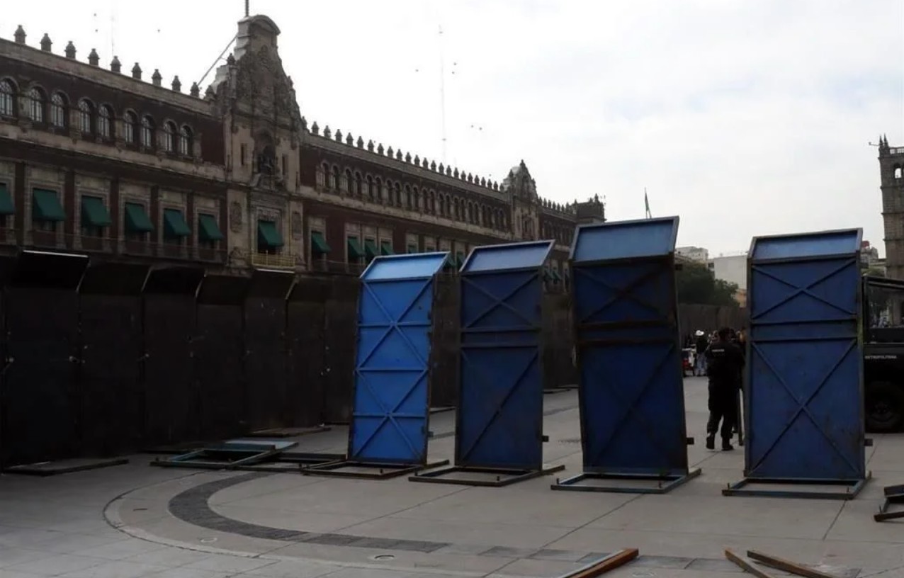 Elementos de seguridad instalan el cerco metálico que cubre la fachada principal de Palacio Nacional.