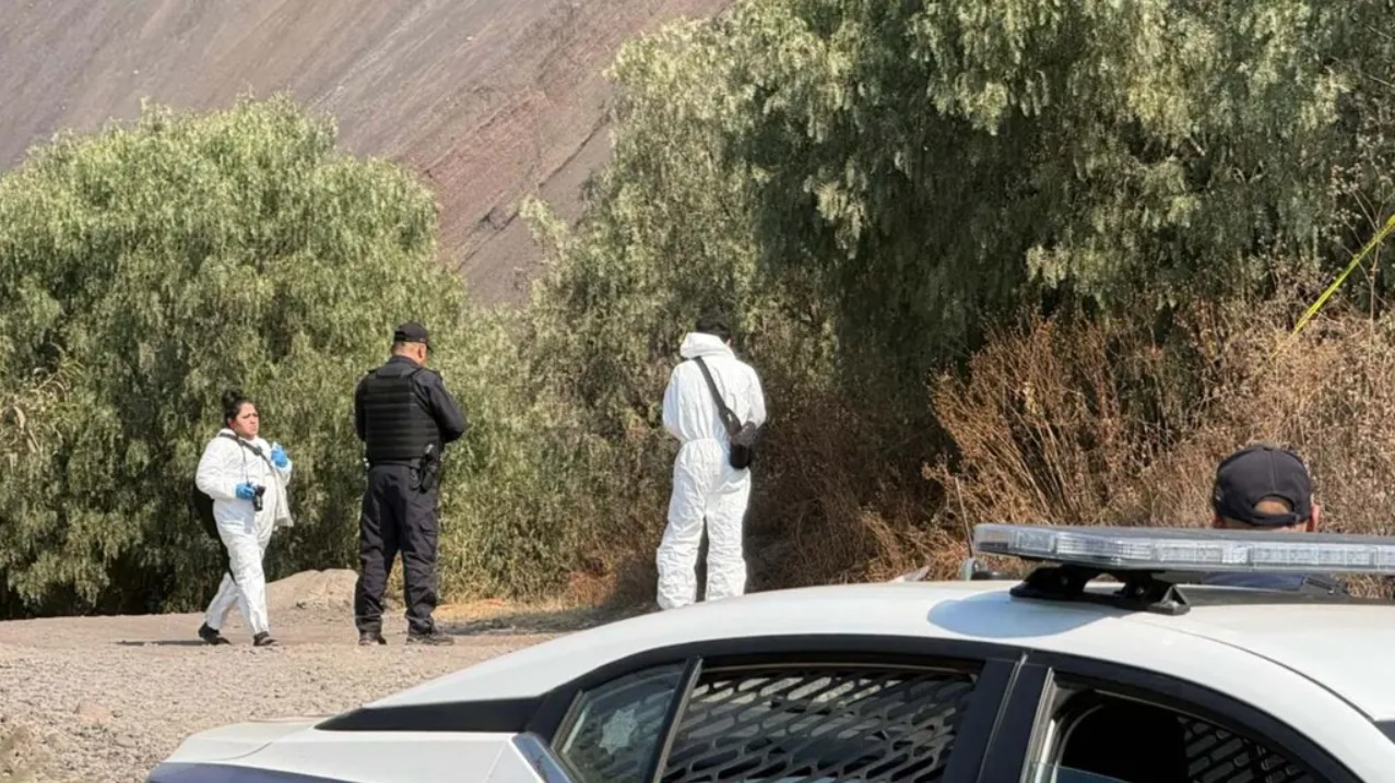 Peritos de la Fiscalía capitalina recolectan evidencias en el camino de terracería donde localizaron la maleta con el cuerpo del menor.