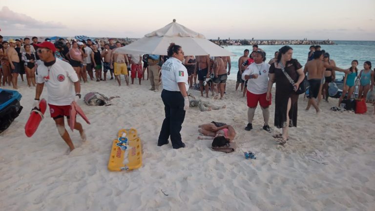 Personal de emergencias atendiendo a los turistas heridos por la moto acuática en la orilla de la playa.