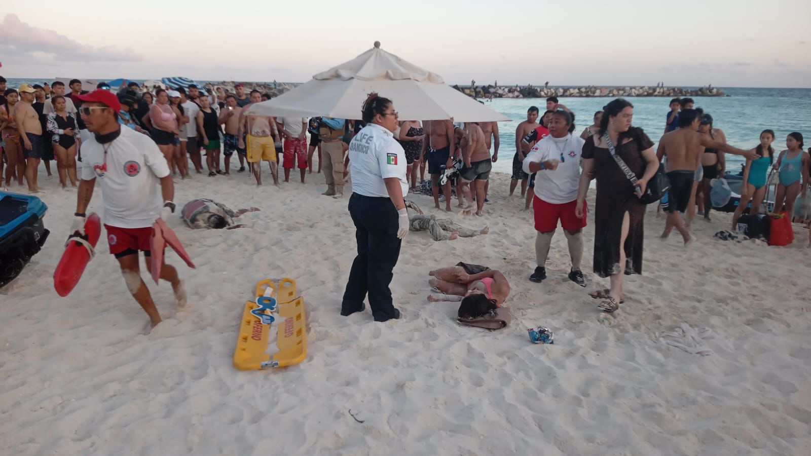 Personal de emergencias atendiendo a los turistas heridos por la moto acuática en la orilla de la playa.