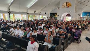 Fieles católicos se agrupan a las afueras de la parroquia Nuestra Señora de Lourdes para presenciar el Viacrucis en Cancún.