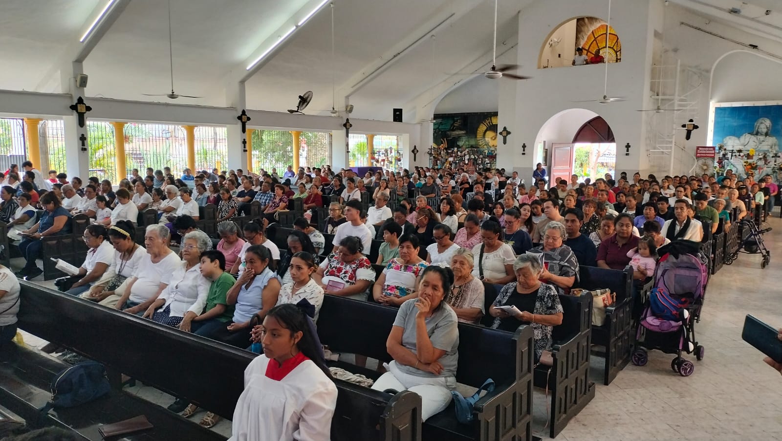 Fieles católicos se agrupan a las afueras de la parroquia Nuestra Señora de Lourdes para presenciar el Viacrucis en Cancún.