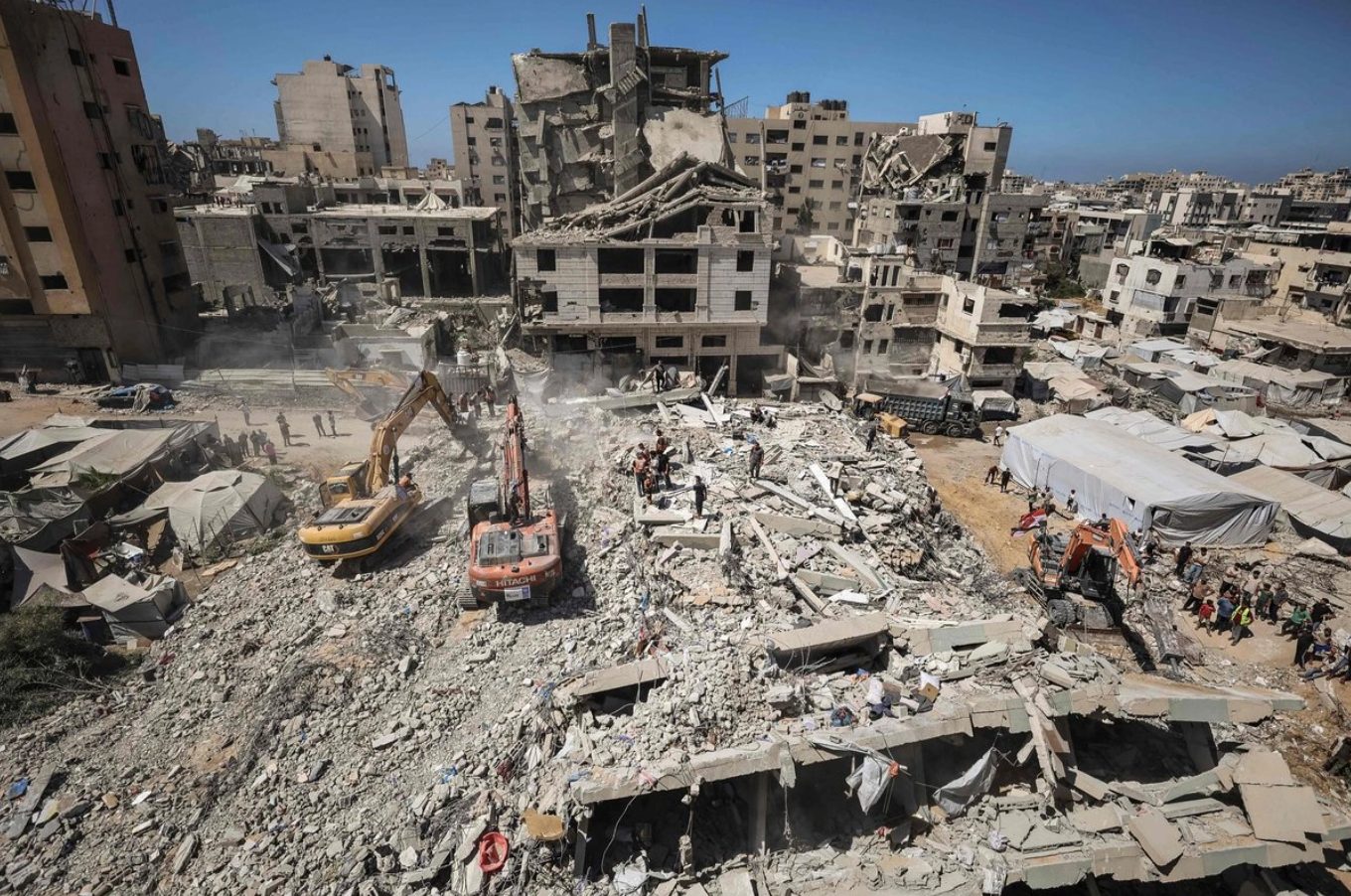 Equipos de rescate y vecinos trabajan con medios rudimentarios entre los escombros del edificio colapsado.
